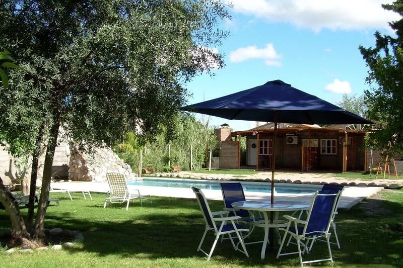 Parque arbolado con mesas, sillas y vista a la pileta